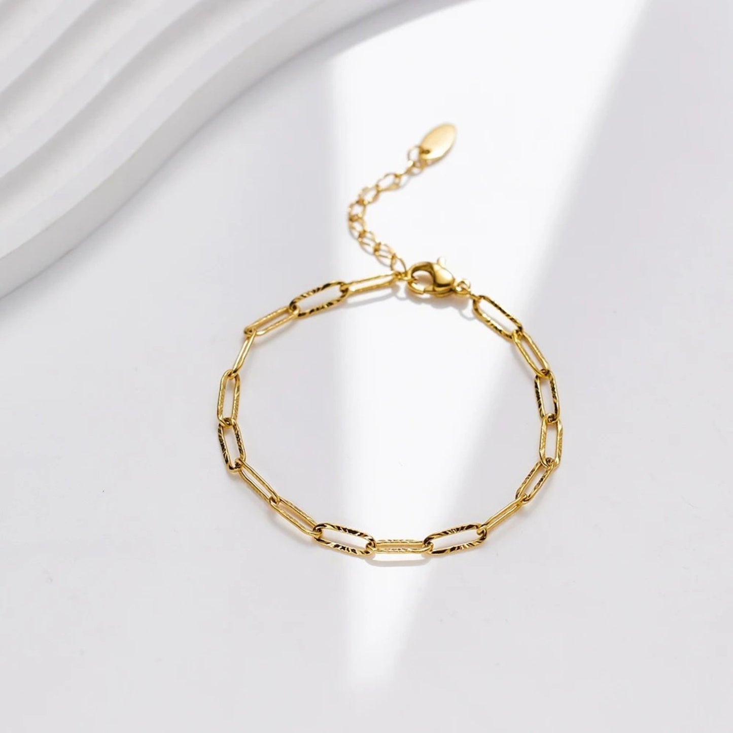Photo with scene background for the 18K gold plated minimalist link chain bracelet made of durable stainless steel, featuring an adjustable length and a secure lobster clasp for a chic and versatile look