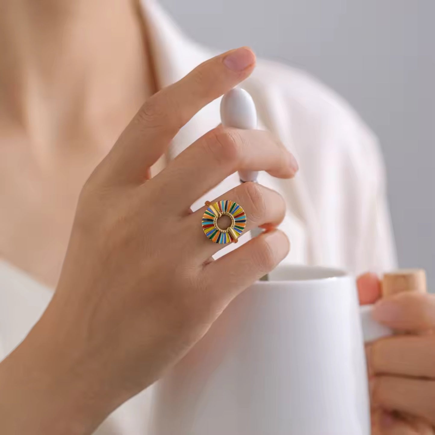 Close-up of the Rainbow Sunburst Adjustable Ring on a model with multicolored enamel segments and 18K gold plating, showcasing intricate details.