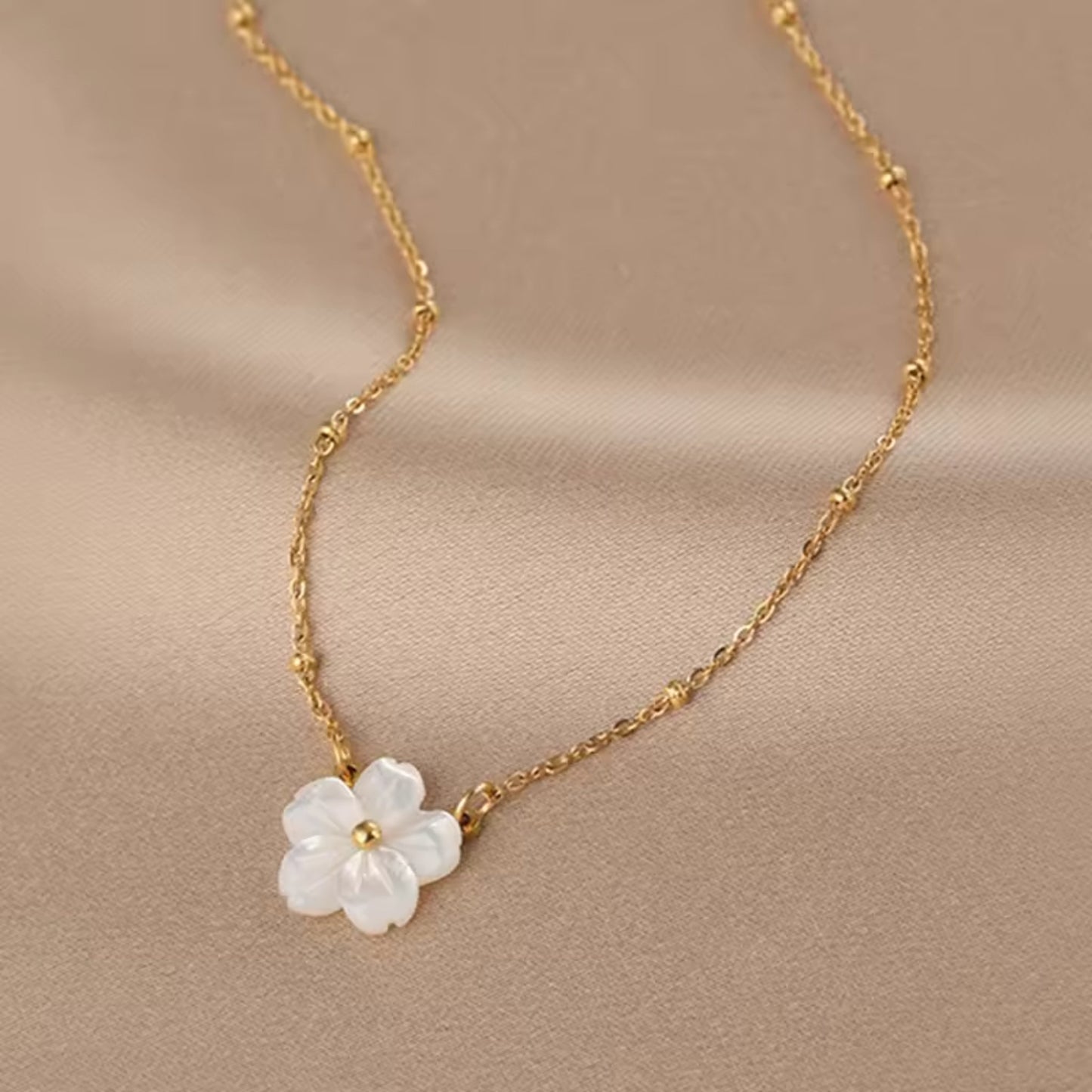 Close-up of the Blossom Beauty Necklace showcasing the lustrous mother of pearl flower pendant with a golden center.