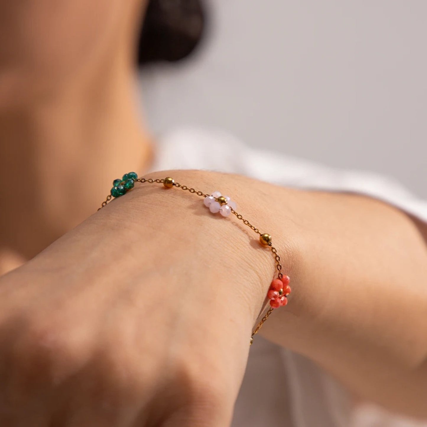 Blossom Radiance Bracelet with 18K gold plating and colorful floral charms, adding a touch of whimsy and sophistication to a model's wrist.