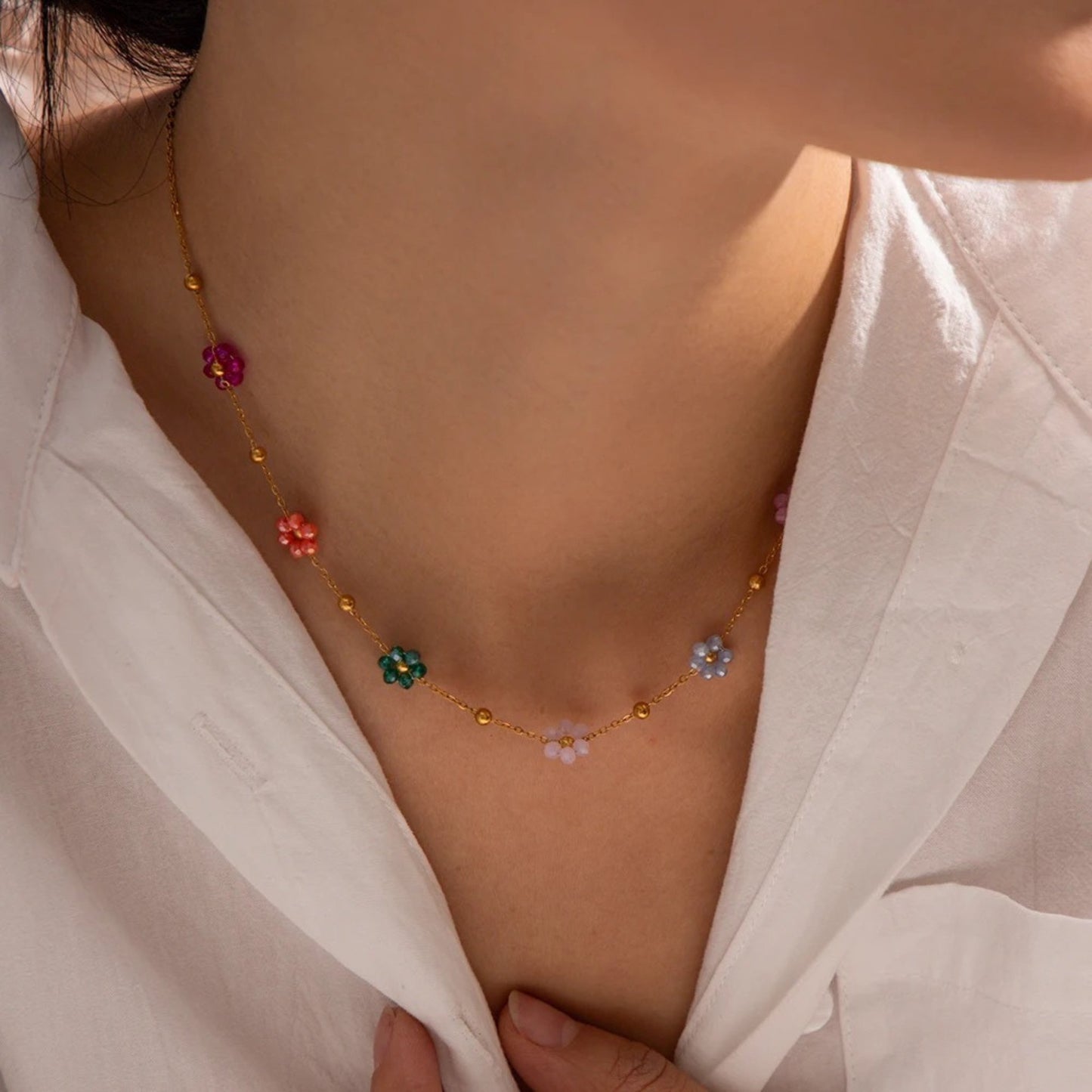 Blossom Radiance Necklace featuring vibrant floral charms and 18K gold-plated design, styled on a model for a chic look.