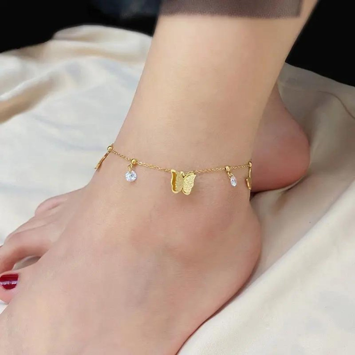 Close-up of the Butterfly Dreams Anklet highlighting its intricate butterfly charms and sparkling crystal drops on a gold-plated chain.