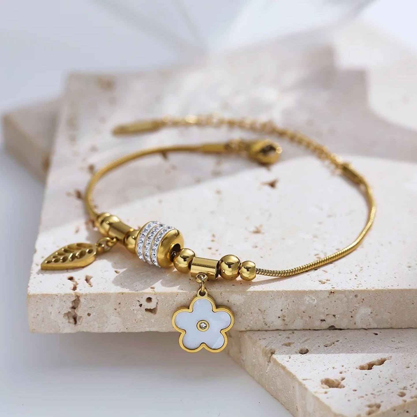 Close-up of the feather and flower charms on the Charm Delight Bracelet, showcasing intricate details and 18K gold plating.