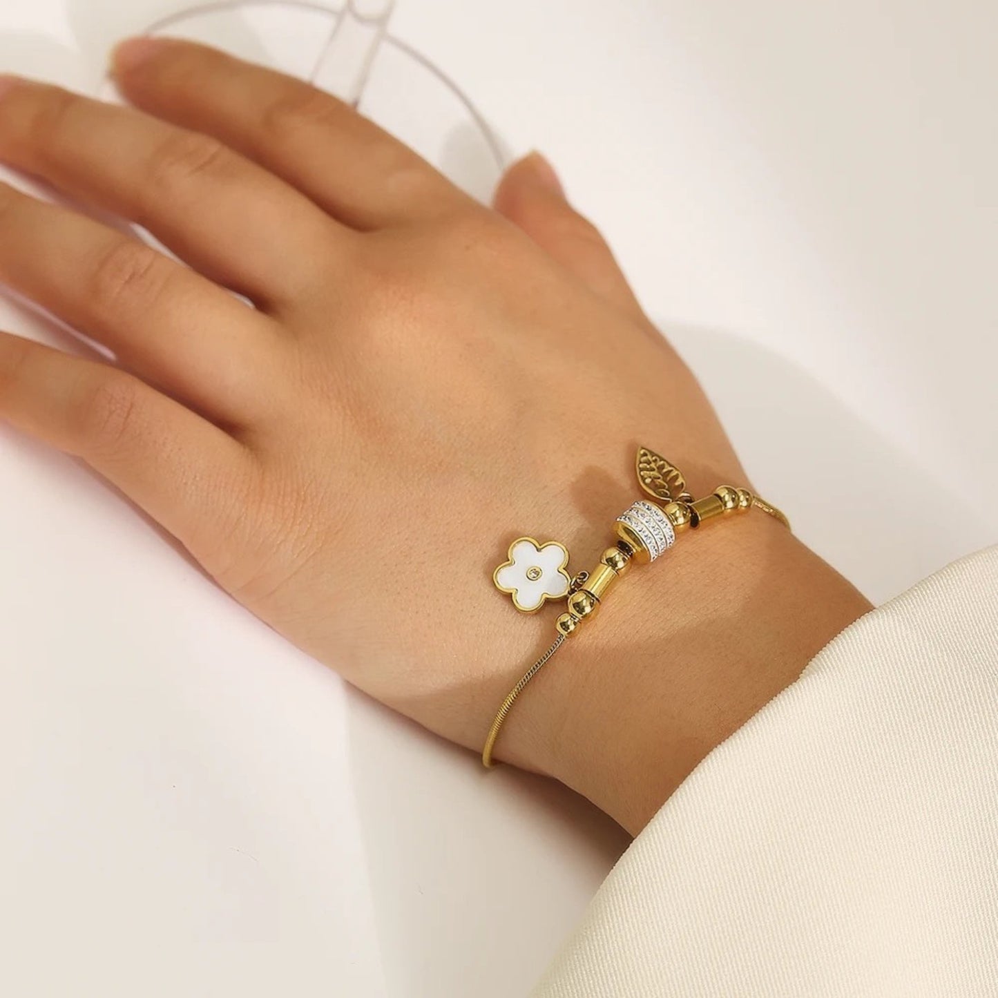 Charm Delight Bracelet styled on a wrist, highlighting its elegant feather and flower charms and adjustable fit.