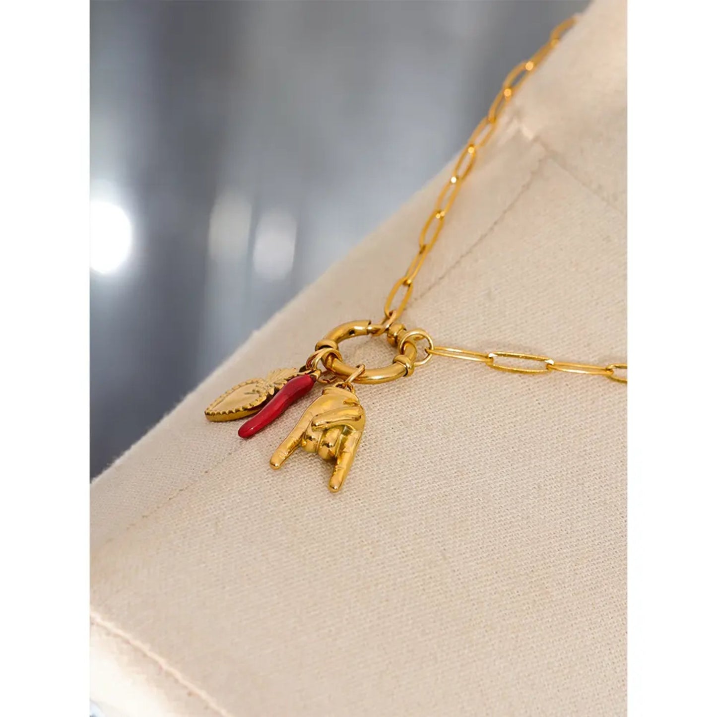 Close-up of the sacred heart, red chili pepper, and hand gesture charms on the Charm of Fortune Necklace, highlighting their symbolic details.