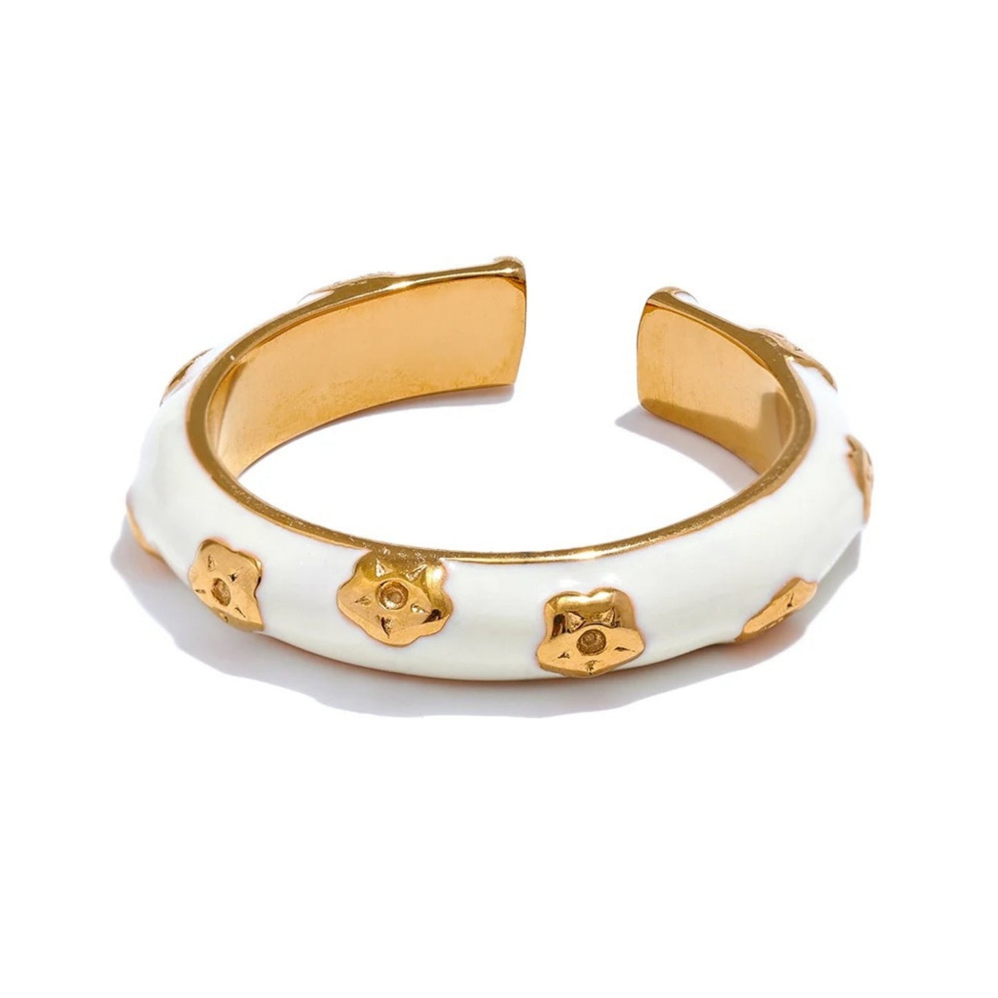 Close-up of the delicate flower motifs on the white enamel band of the adjustable gold-plated ring.