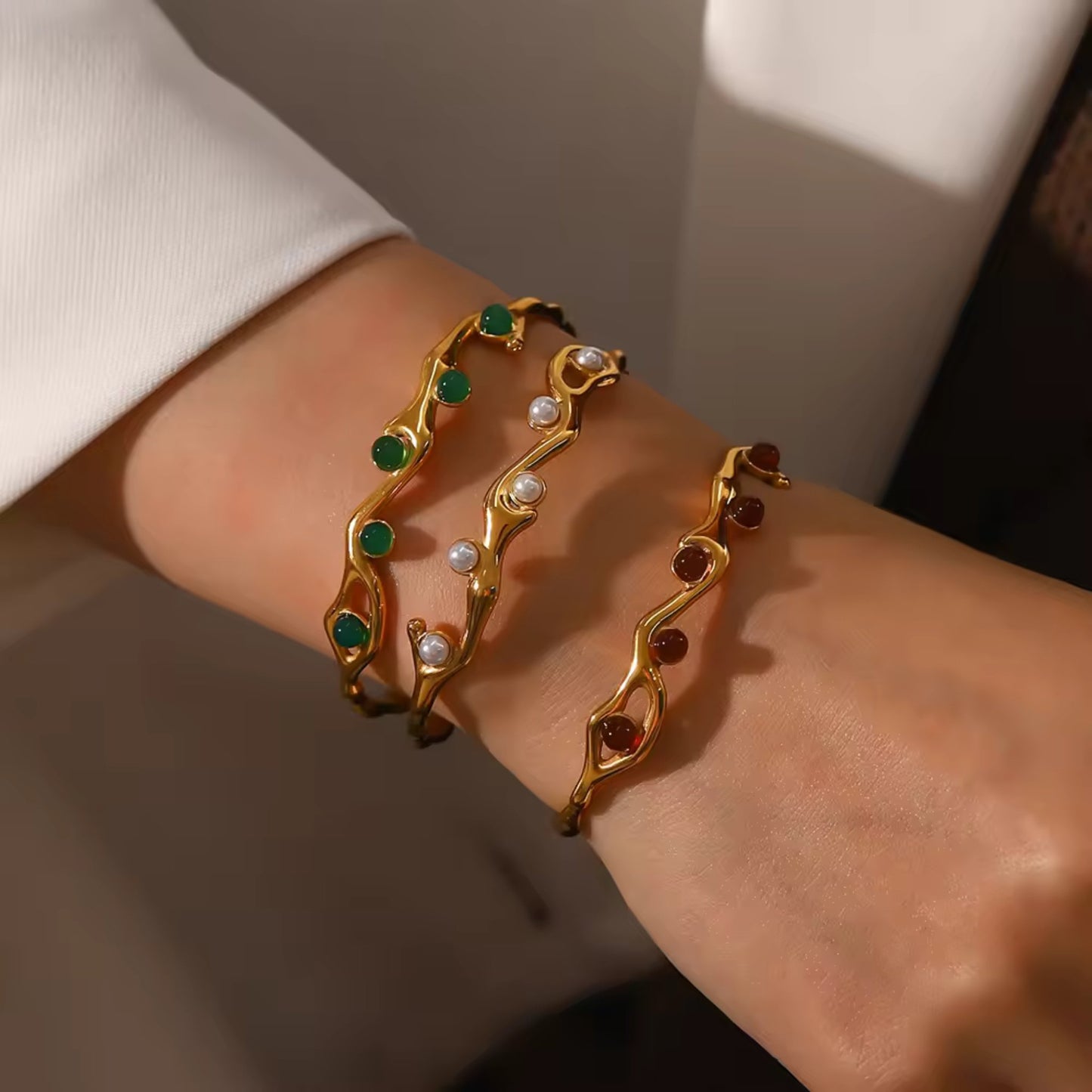 Model wearing the 18K gold plated adjustable vine bangle bracelet with a choice of freshwater pearl, green gemstone, or red gemstone, featuring a delicate vine design and durable stainless steel construction