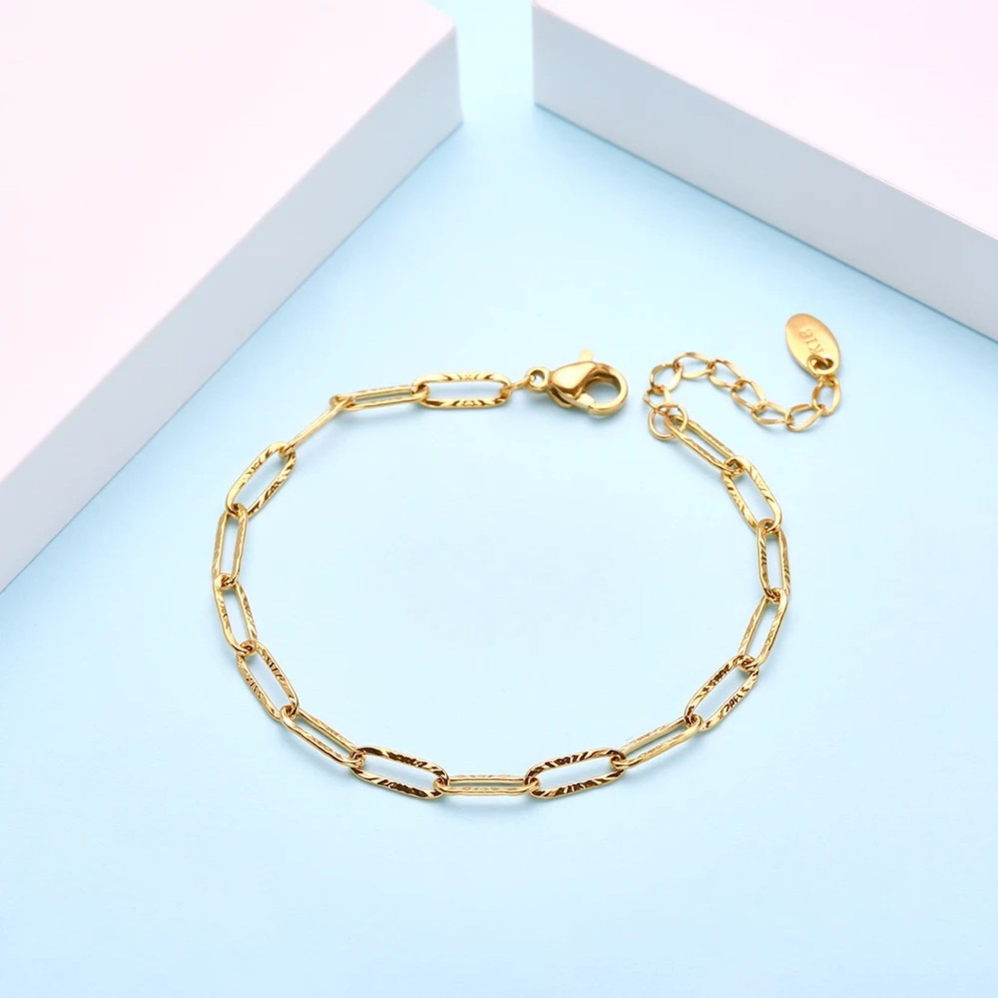 Photo with background scene for the 18K gold plated minimalist link chain bracelet made of durable stainless steel, featuring an adjustable length and a secure lobster clasp for a chic and versatile look