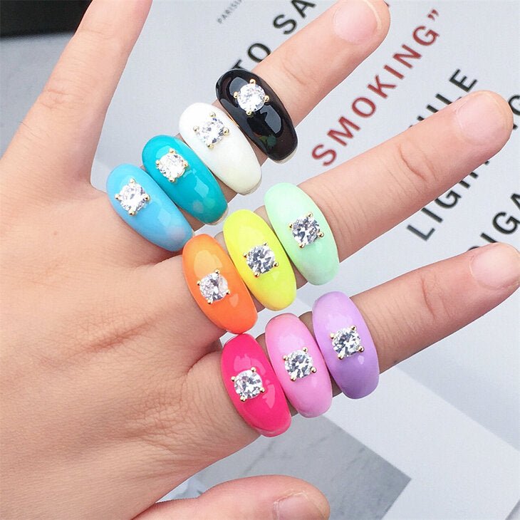 Model wearing 18K Gold Plated Oil Dripping Cubic Zirconia Rings in vibrant colors: Orange, Yellow, Purple, and Turquoise,
