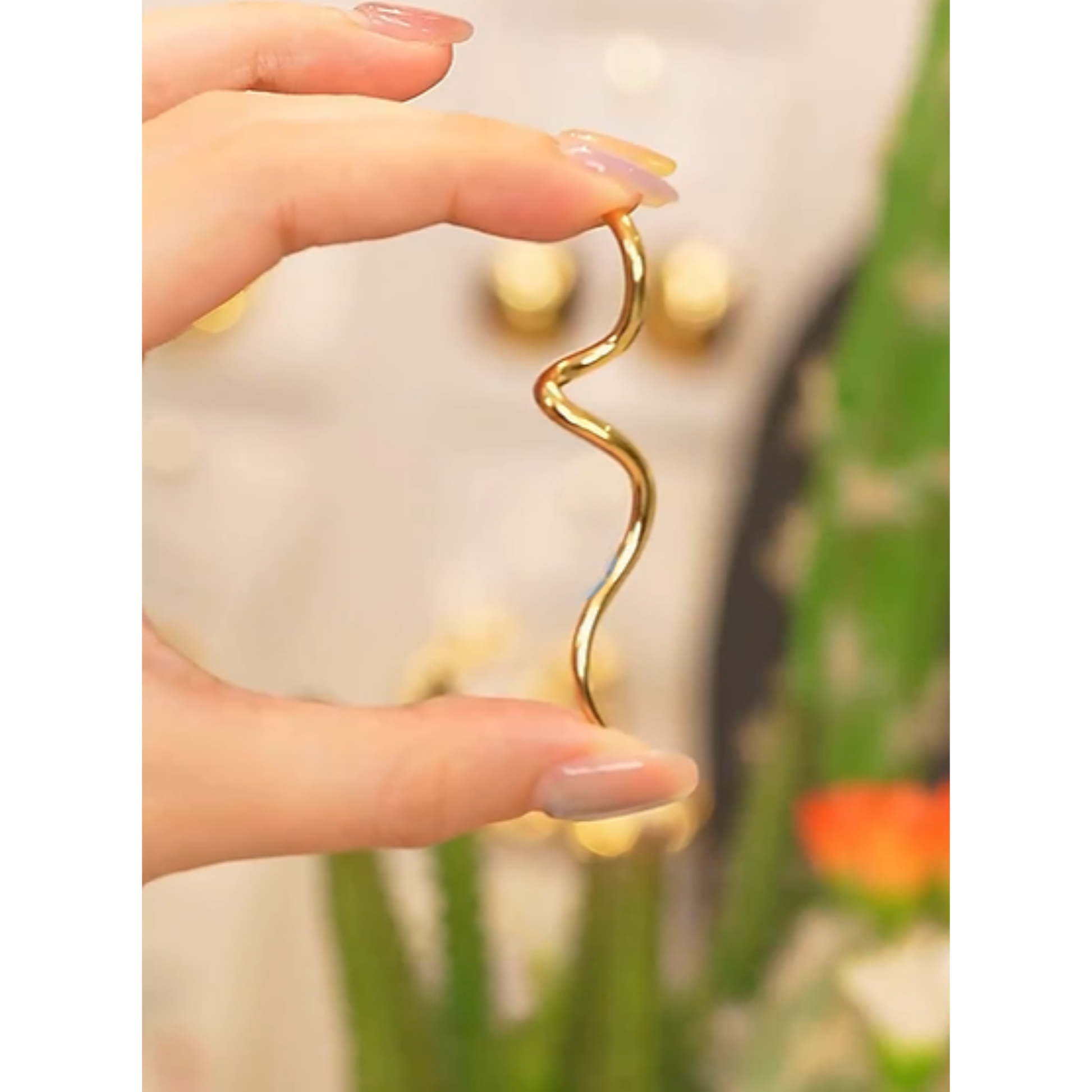 Close-up of the Curved Minimalist Gold Drop Earrings.