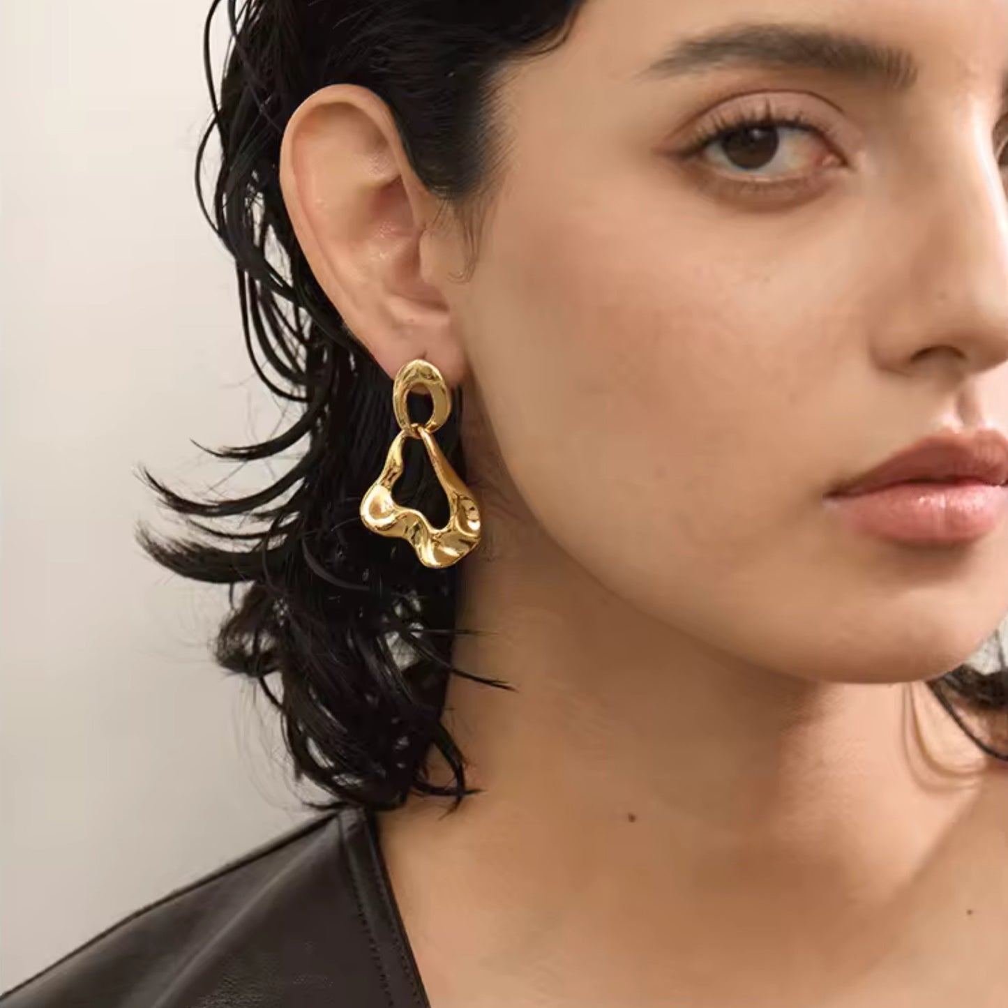 Abstract Luxe Gold Dangle Earrings featuring bold 18K PVD gold-plated stainless steel with a fluid abstract design, shown on a model for a striking look.