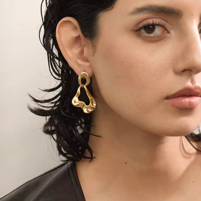 Abstract Luxe Gold Dangle Earrings featuring bold 18K PVD gold-plated stainless steel with a fluid abstract design, shown on a model for a striking look.