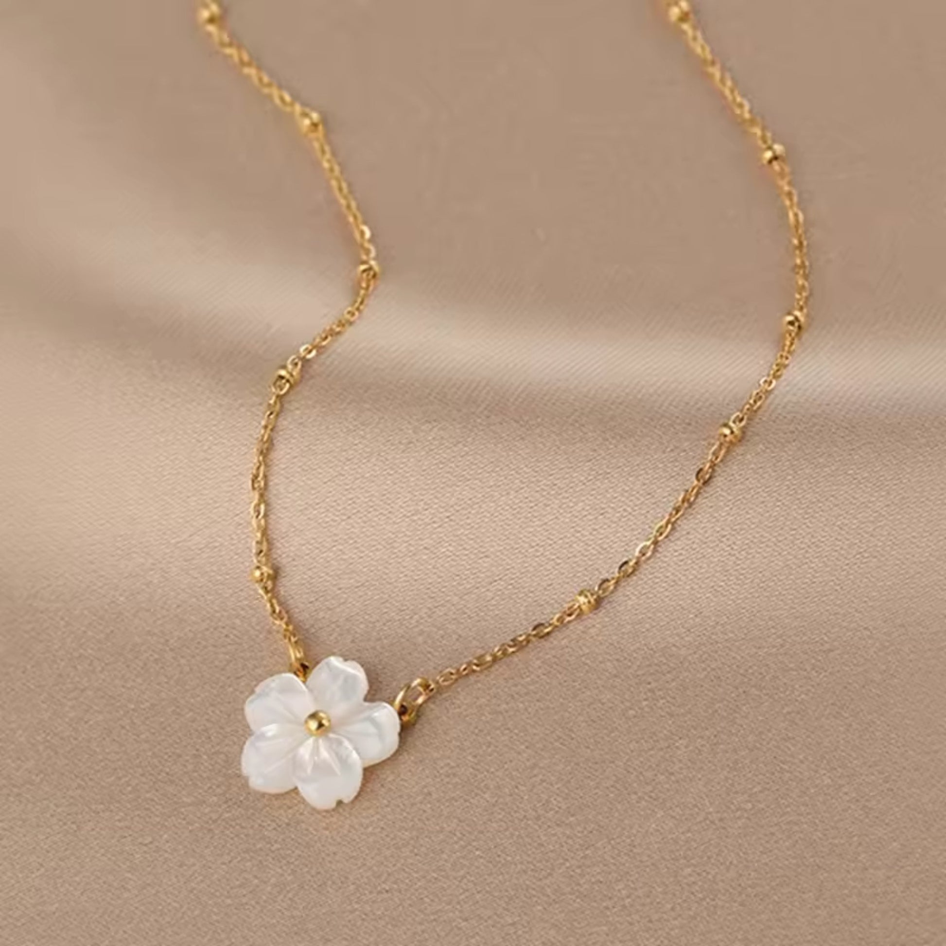 Close-up of the Blossom Beauty Necklace showcasing the lustrous mother of pearl flower pendant with a golden center.
