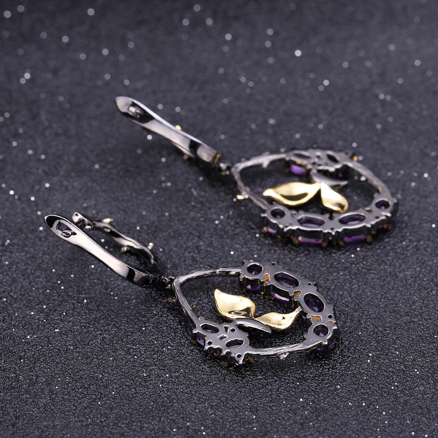 Close-up of Amethyst and Emerald Sterling Silver Earrings showcasing oval-shaped amethyst stones, nano emerald accents, and intricate branch details in black gun and gold plating.
