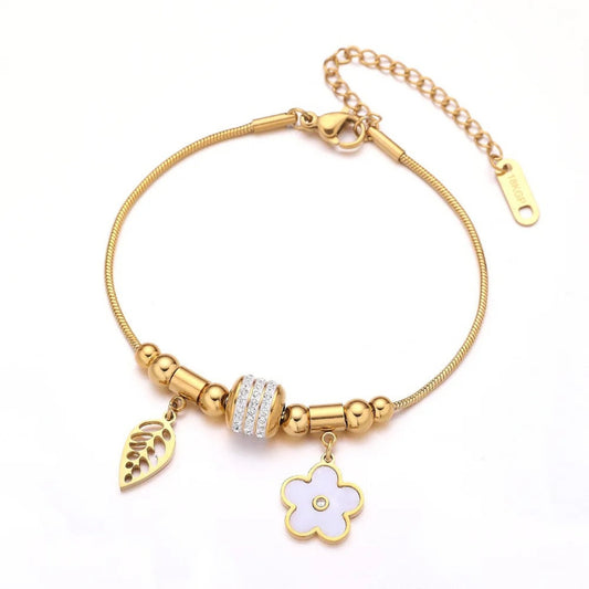 Charm Delight Bracelet crafted from 18K gold-plated stainless steel with delicate feather and flower charms and a sparkling cubic zirconia bead.