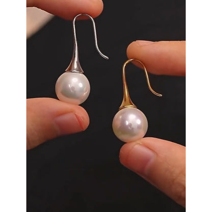Holding the Gold and Silver Elegance Pearl Drop Earrings, perfect for casual and formal occasions.
