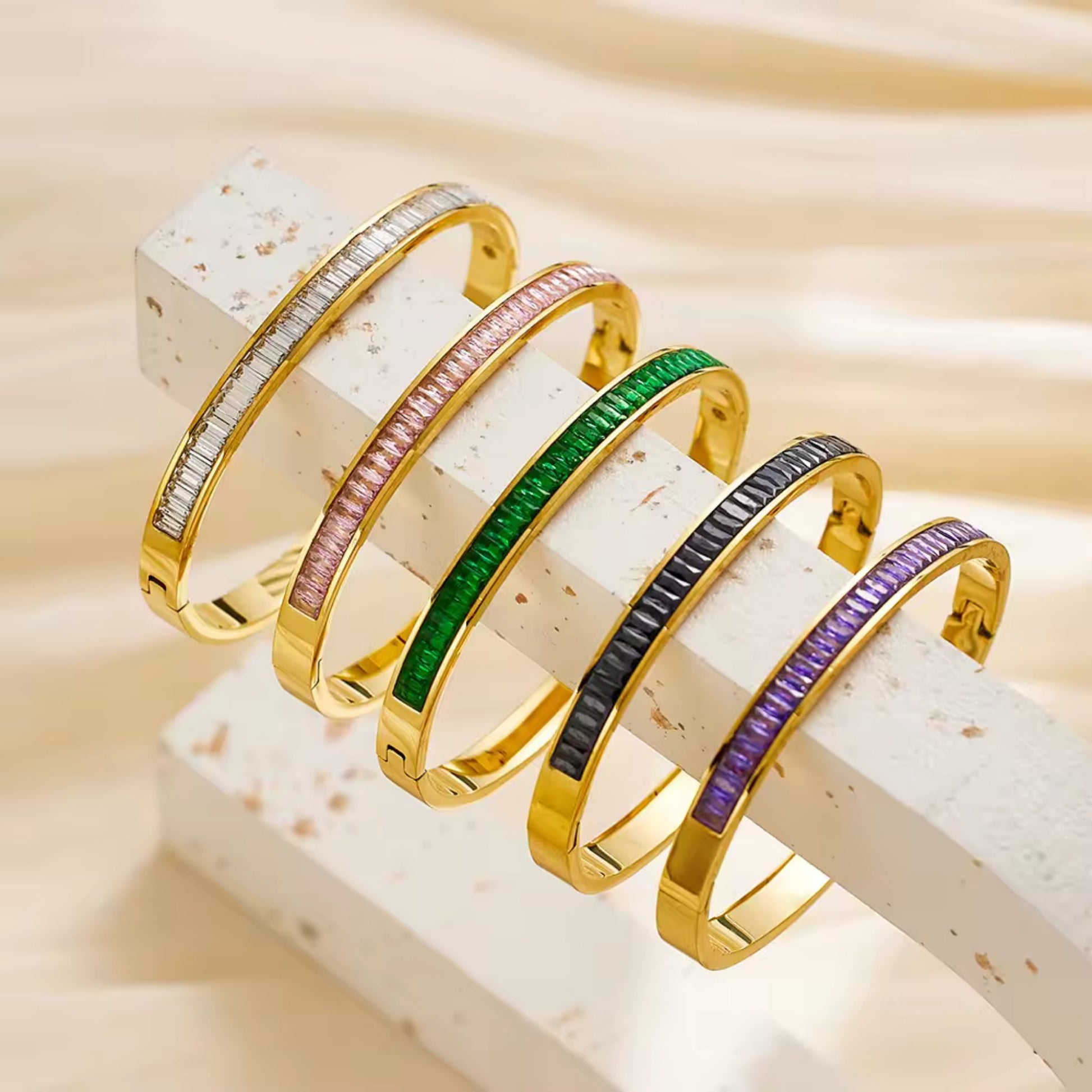 Flat-lay of all five color options: White, Pink, Purple, Green, and Black CZ Gold Plated Bangle Bracelets.