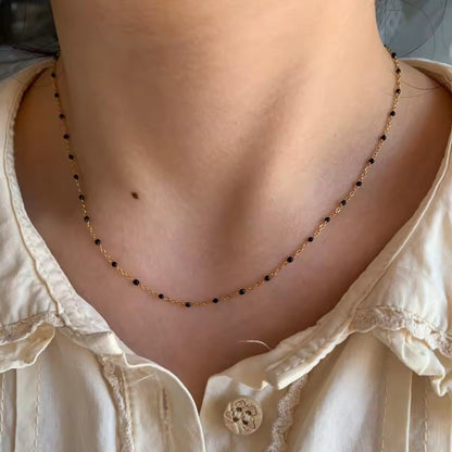 Elegant Cascade Necklace with 18K gold-plated chain and black bead accents, styled for a chic look.