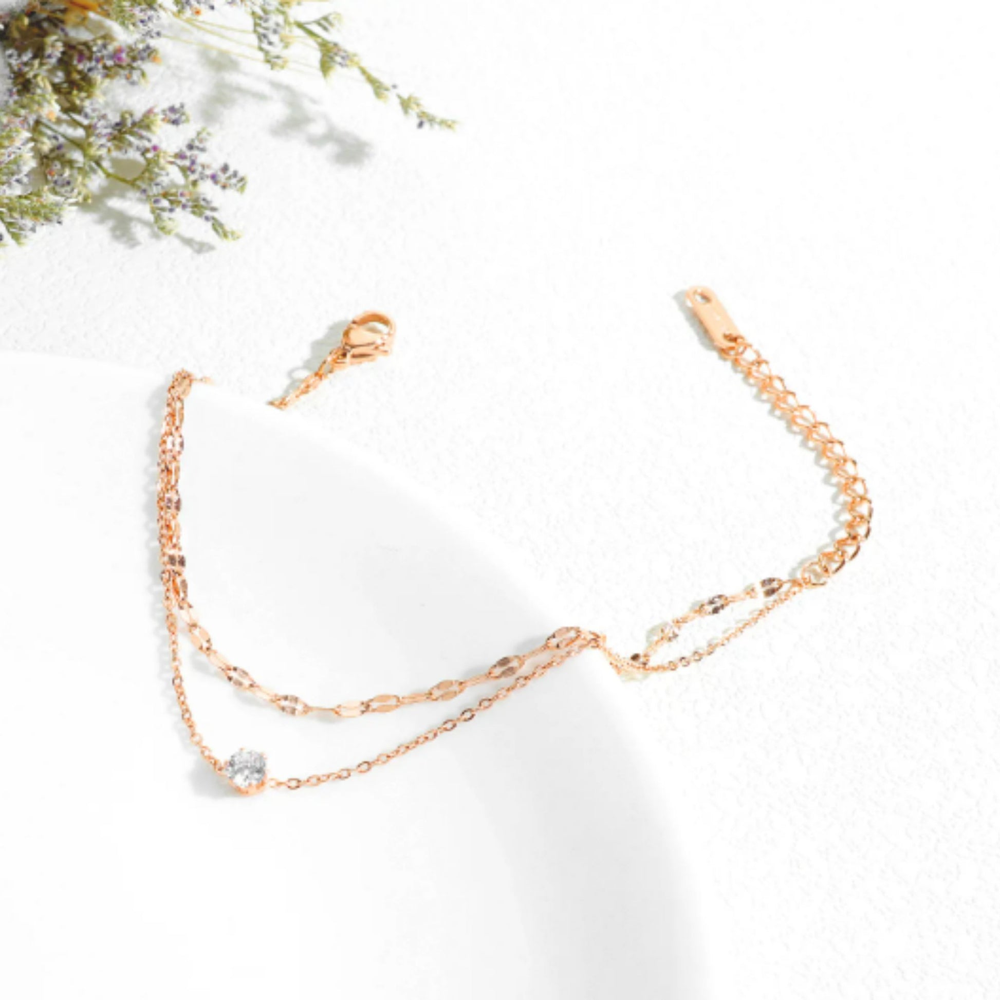 Flat-lay of the 18K rose gold anklet highlighting its minimalist double-layer design and zircon accent.