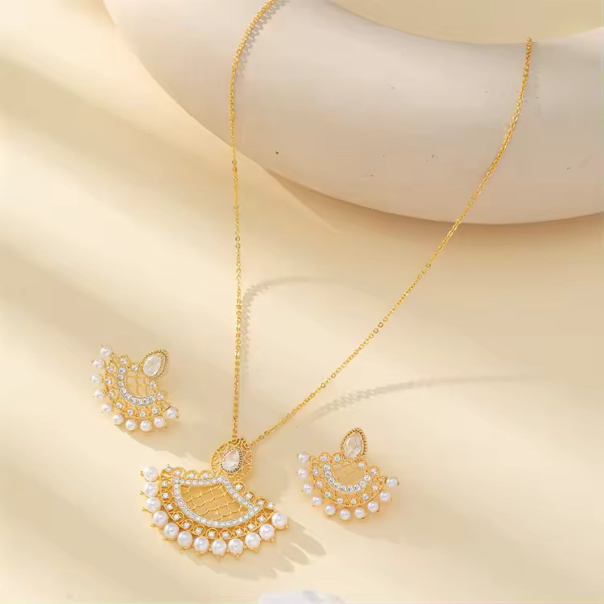 Flat-lay of the necklace and earrings set with 18K gold plating and pearls, perfect for weddings and formal occasions.