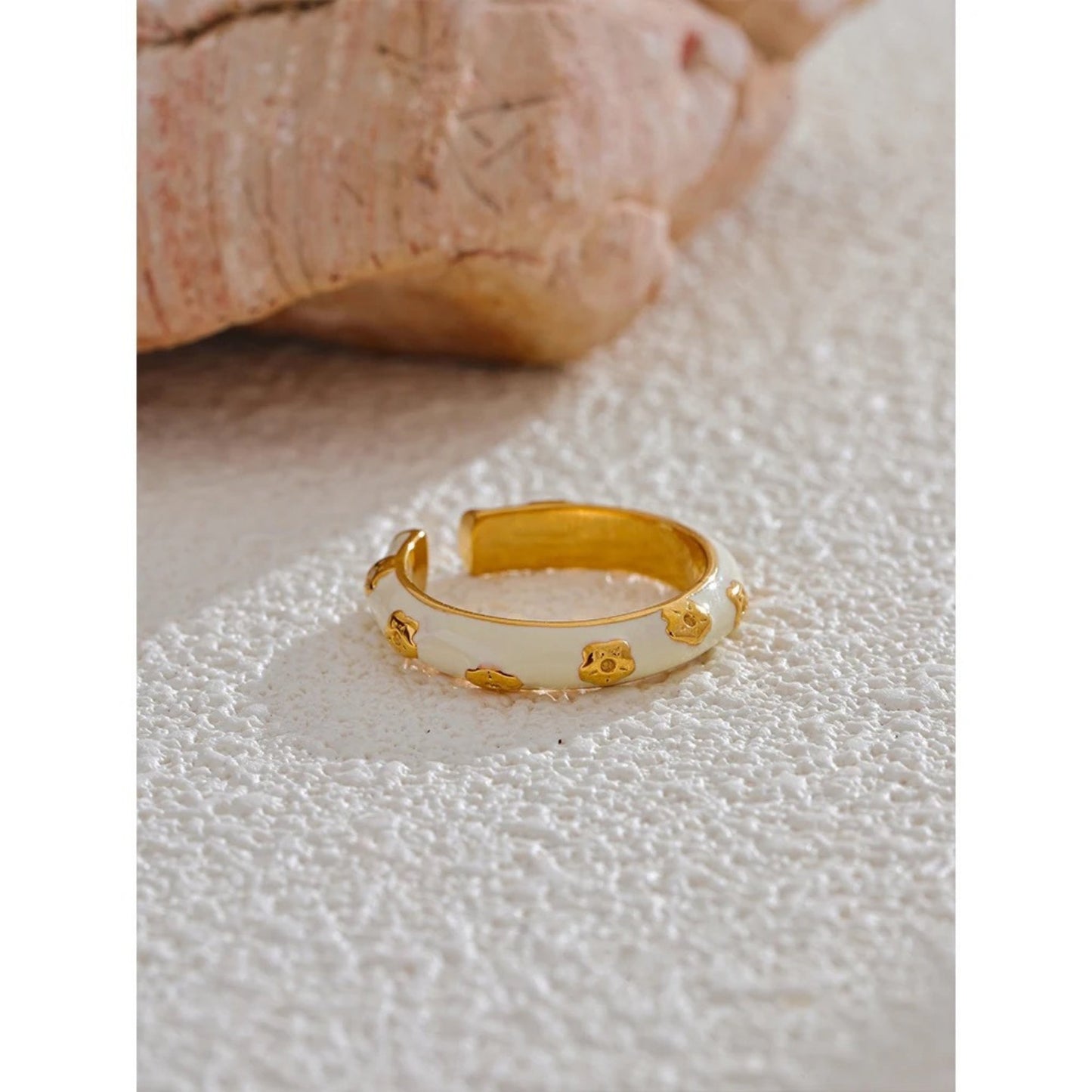 Flat-lay display of the gold-plated White Enamel Flower Ring alongside complementary jewelry pieces.