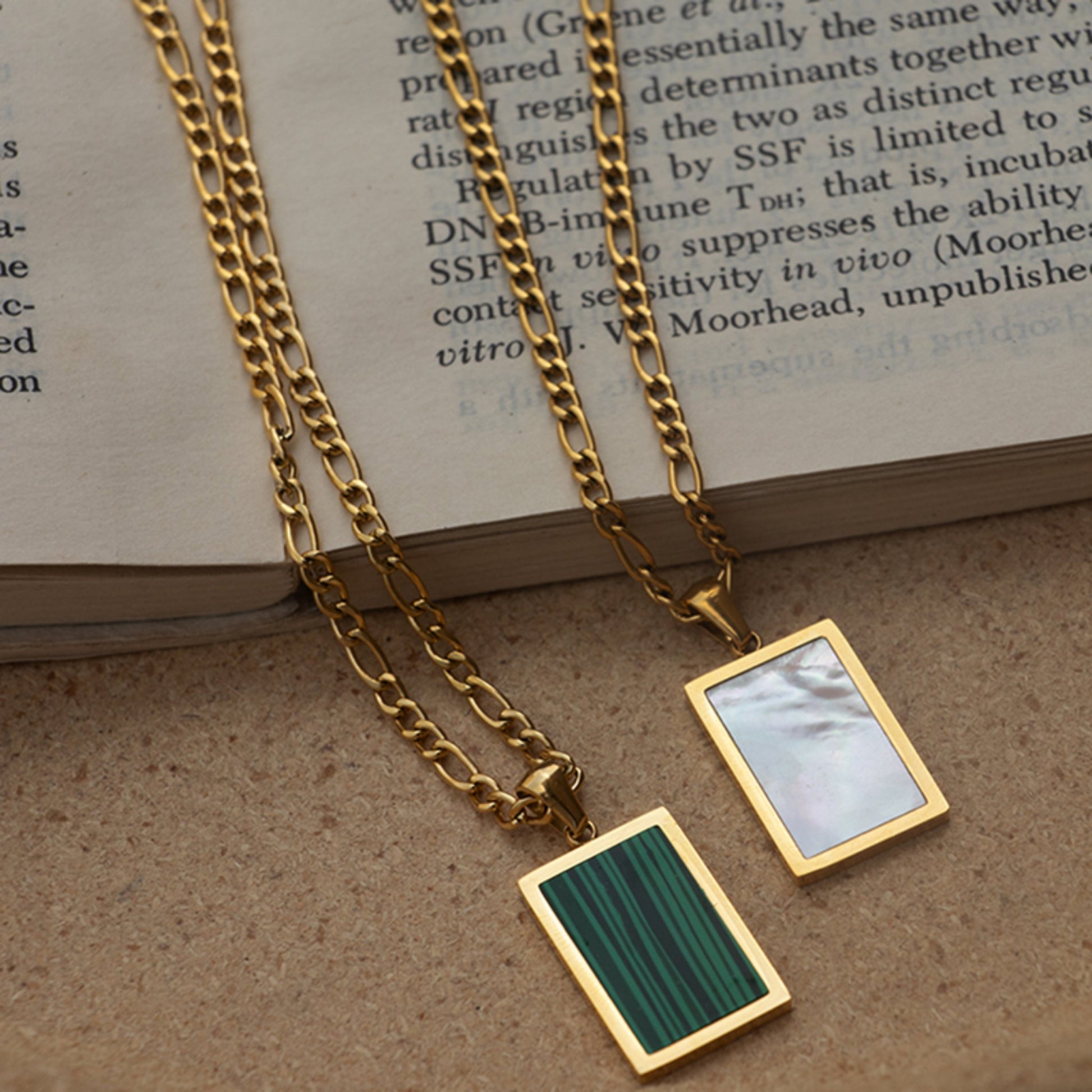 Side-by-side display of 18K gold-plated rectangular pendant necklaces featuring natural green malachite and white shell stone pendants on stainless steel chains.