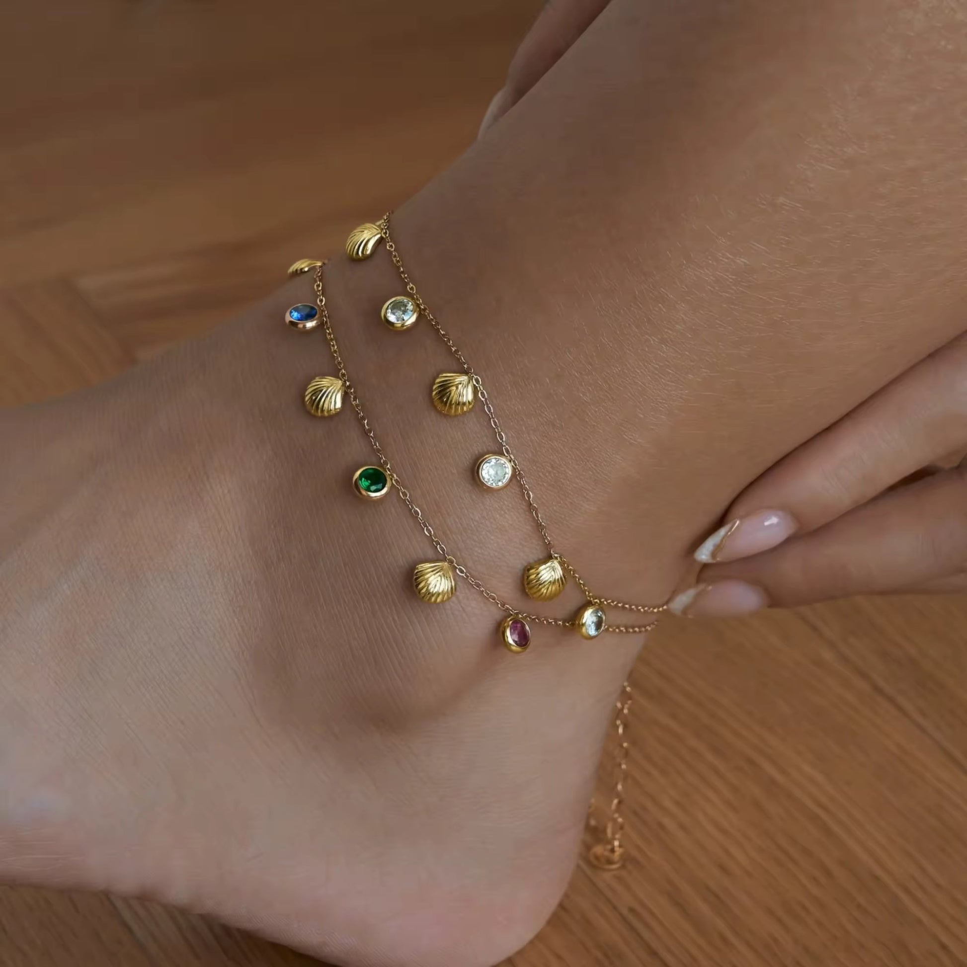 Model displaying a playful 18K gold-plated seashell anklet with multicolored and white zircon stones, adding a chic touch to a summery outfit.