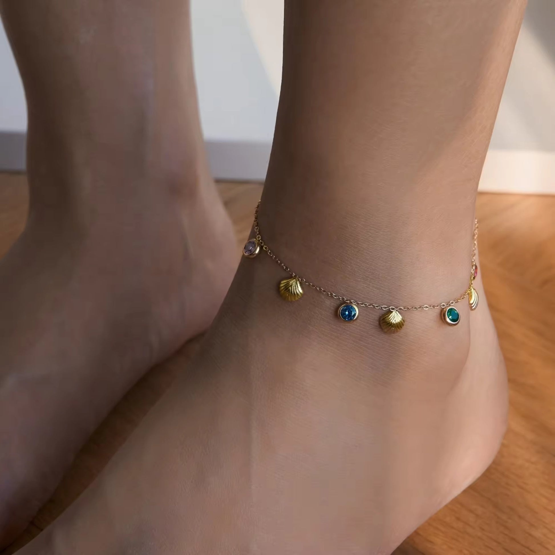 Model displaying a playful 18K gold-plated seashell anklet with multicolored zircon stones, adding a chic touch to a summery outfit.