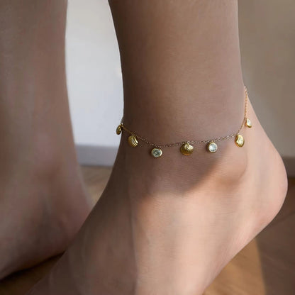 Model wearing an elegant 18K gold-plated seashell anklet with white zircons, styled for a beach outing or casual summer day.