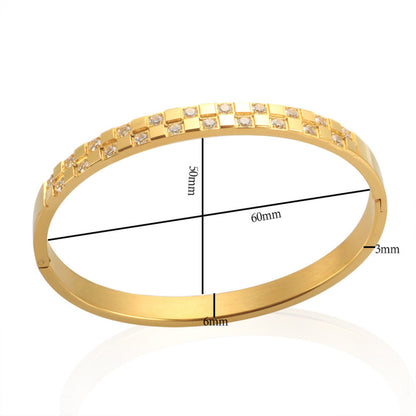 Details photo Close-up of a gold-plated stainless steel cuff bracelet with a checkered pattern of cubic zirconia stones, displayed on a white background.