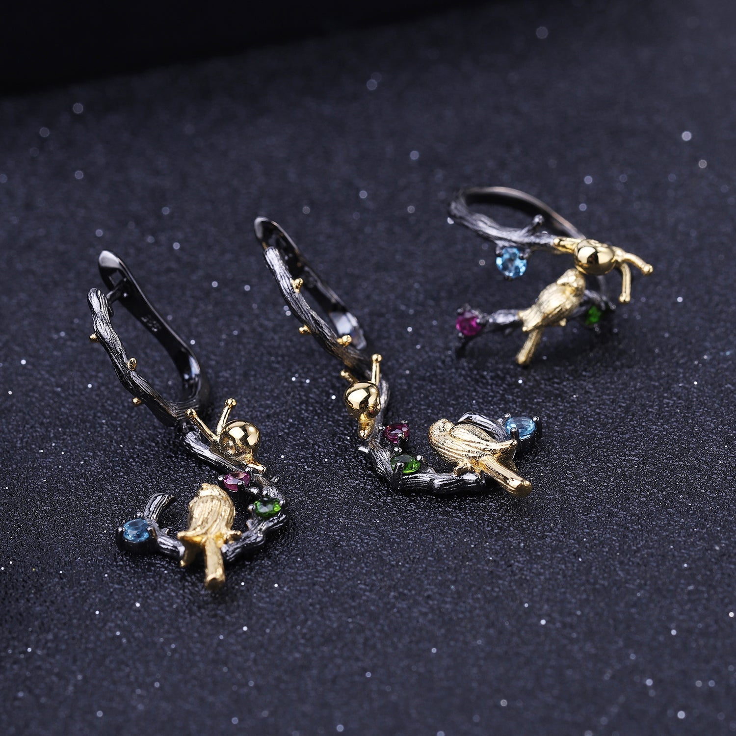 Detailed view of Swiss Blue Topaz, amethyst, and peridot stones on 925 Sterling Silver Bird & Snail Earrings with black gun and gold plating.