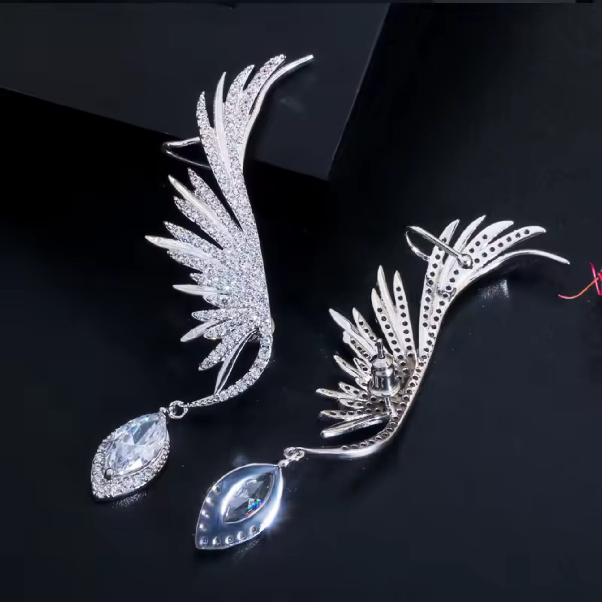 Close-up of Enchanted Wings Feather Drop Earrings with white zircons, highlighting the brilliant-cut stones and feather wing detailing.