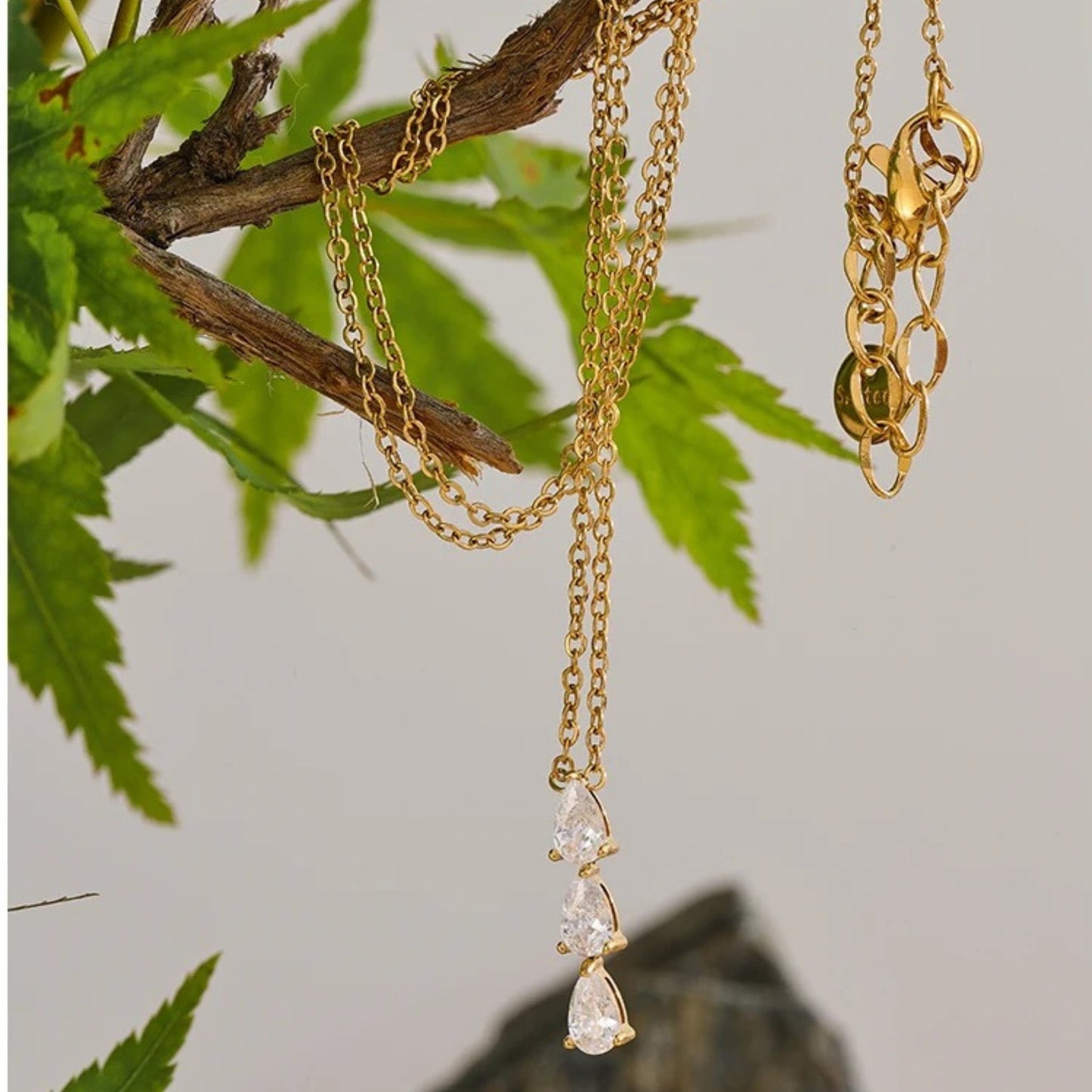 Exquisite Shimmer Necklace laid flat, highlighting its 18K gold-plated chain and shimmering trio zirconia pendant.