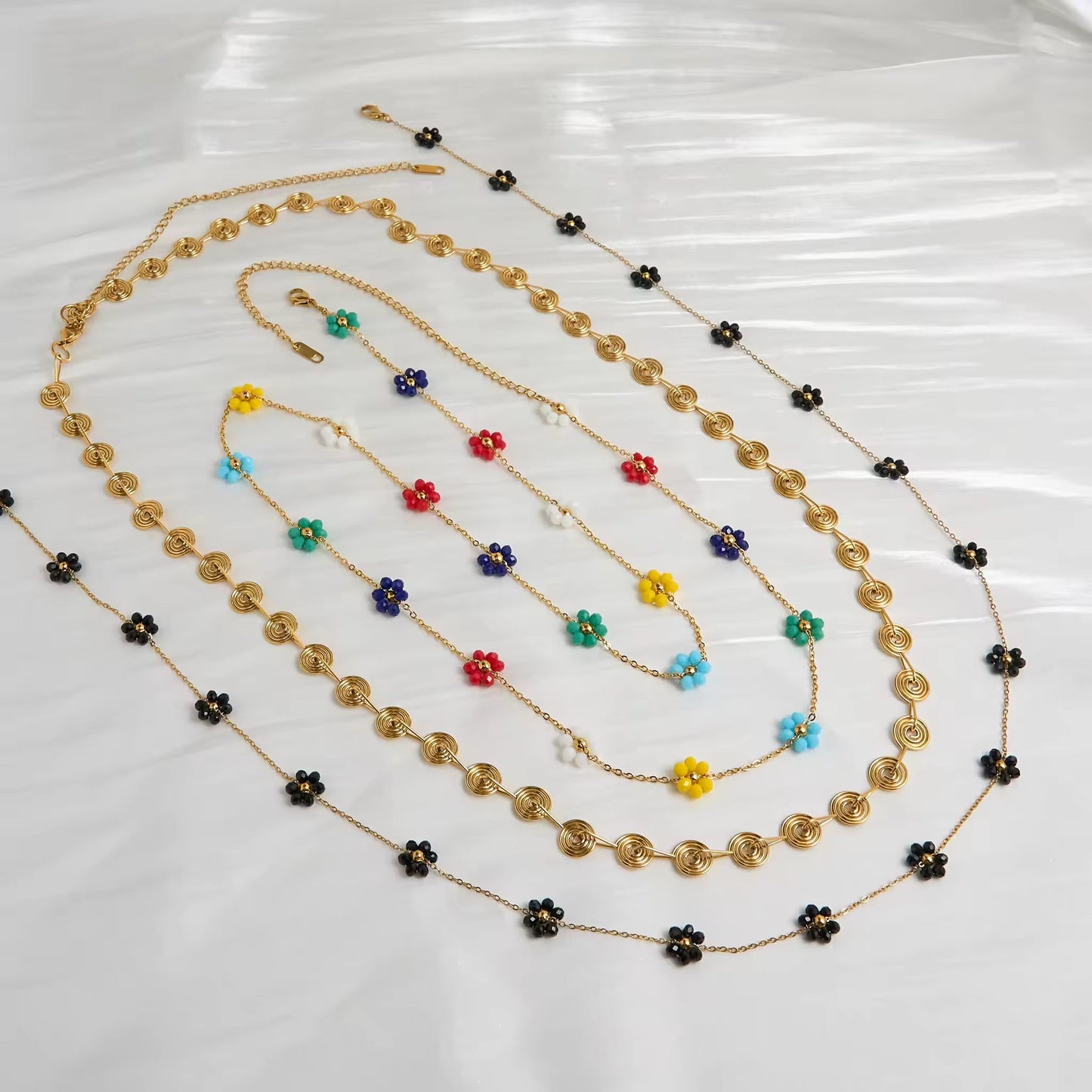 Floral Harmony Belly Chain Set displayed on a flat lay, showcasing the trio—Golden Spiral, Midnight Bloom, and Rainbow Blossom.