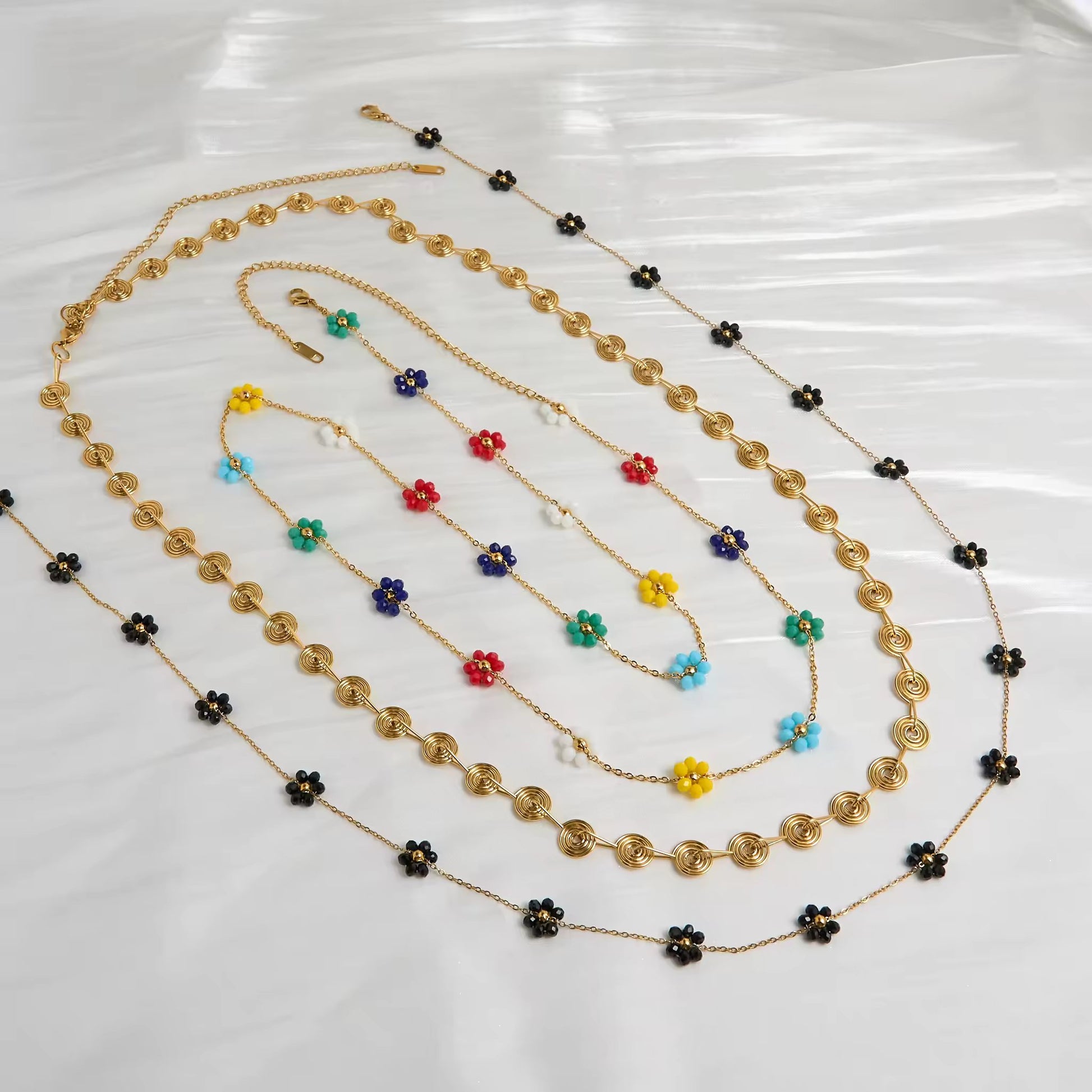 Floral Harmony Belly Chain Set displayed on a flat lay, showcasing the trio—Golden Spiral, Midnight Bloom, and Rainbow Blossom.